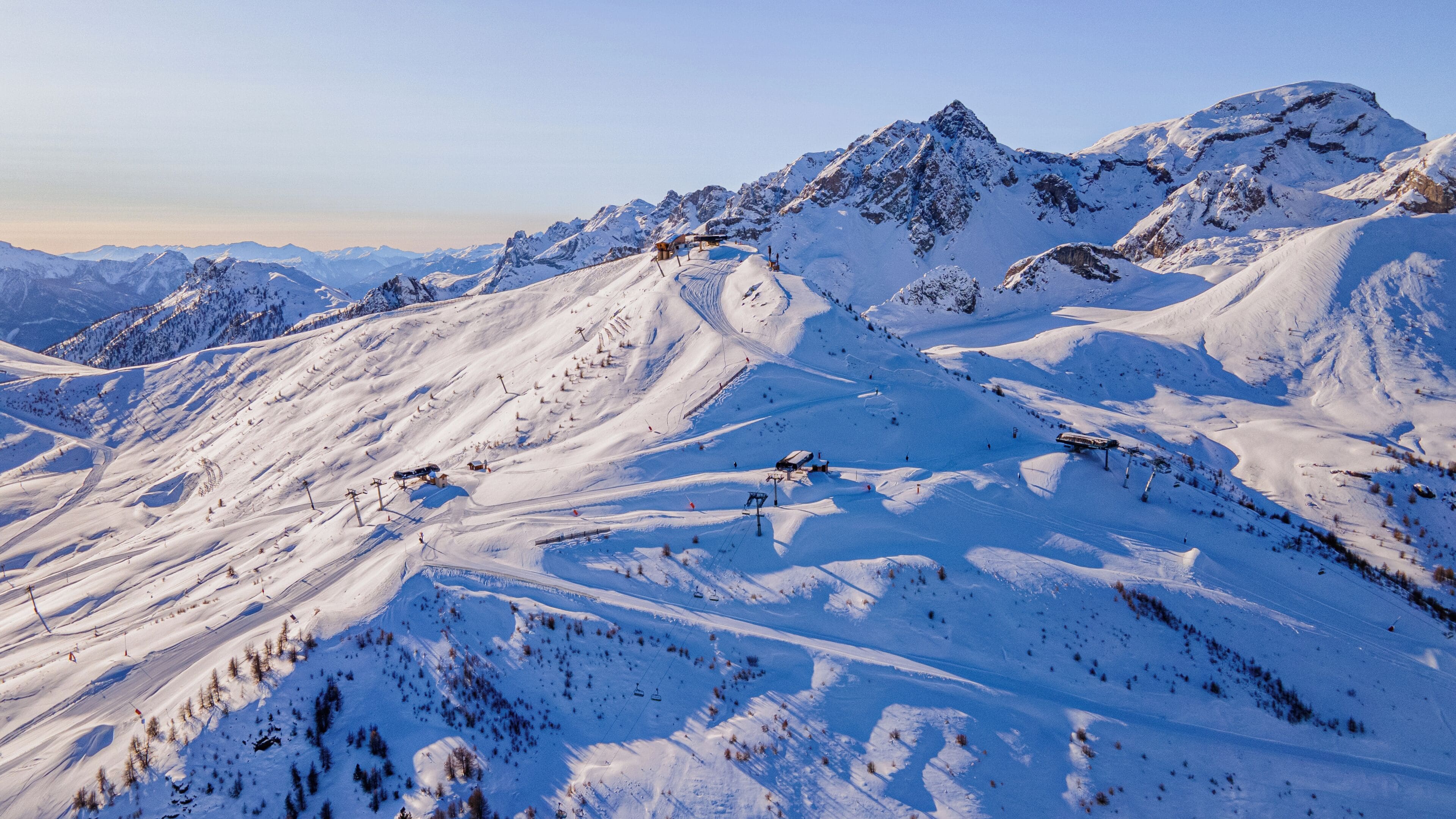 A snow-covered mountain landscape with ski lifts and a small building.