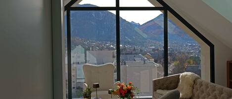 A modern room with a large window offering a view of mountains and a cityscape.