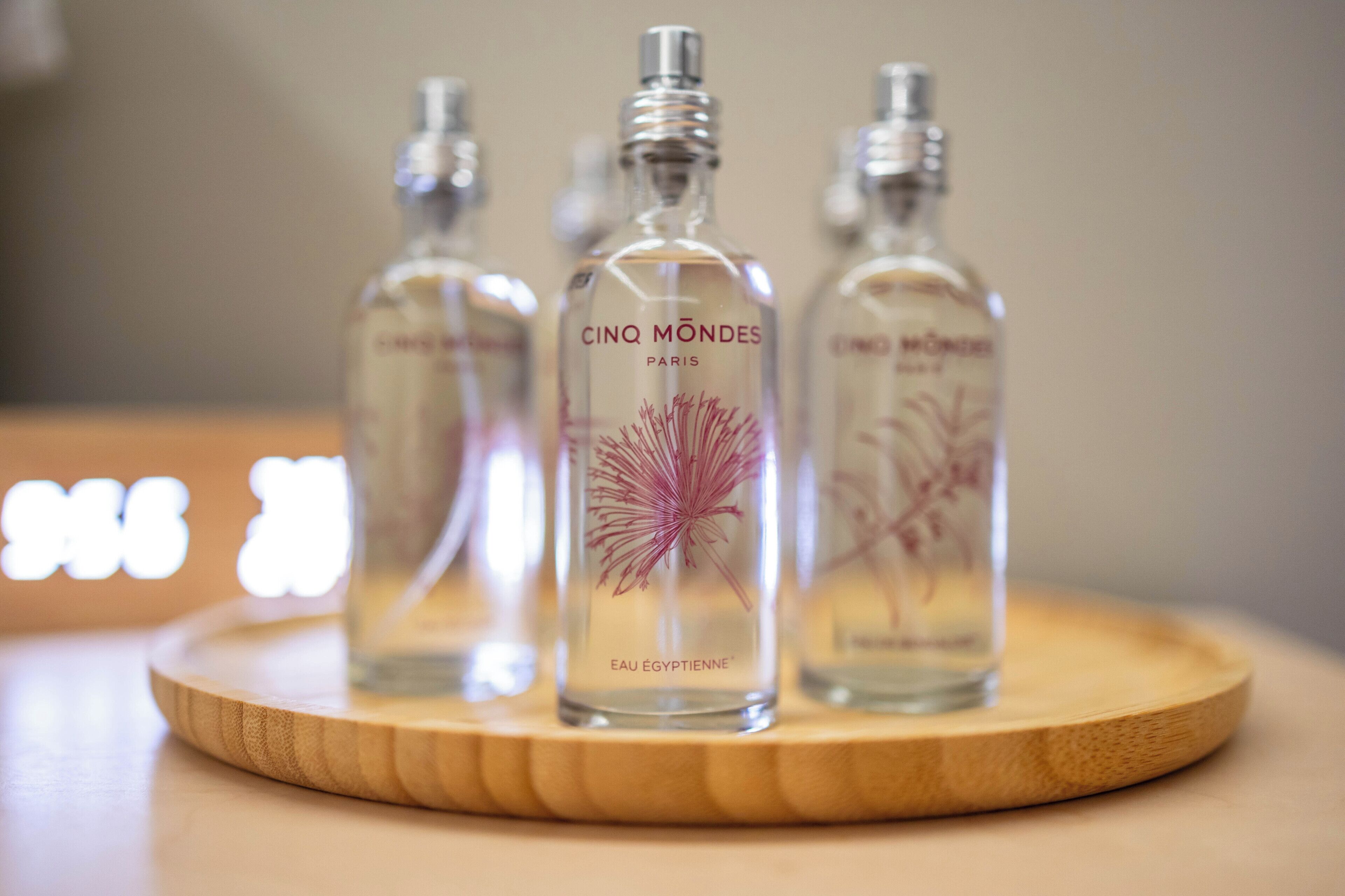 Three bottles of Cinq Mondes Paris eau de toilette on a wooden tray.