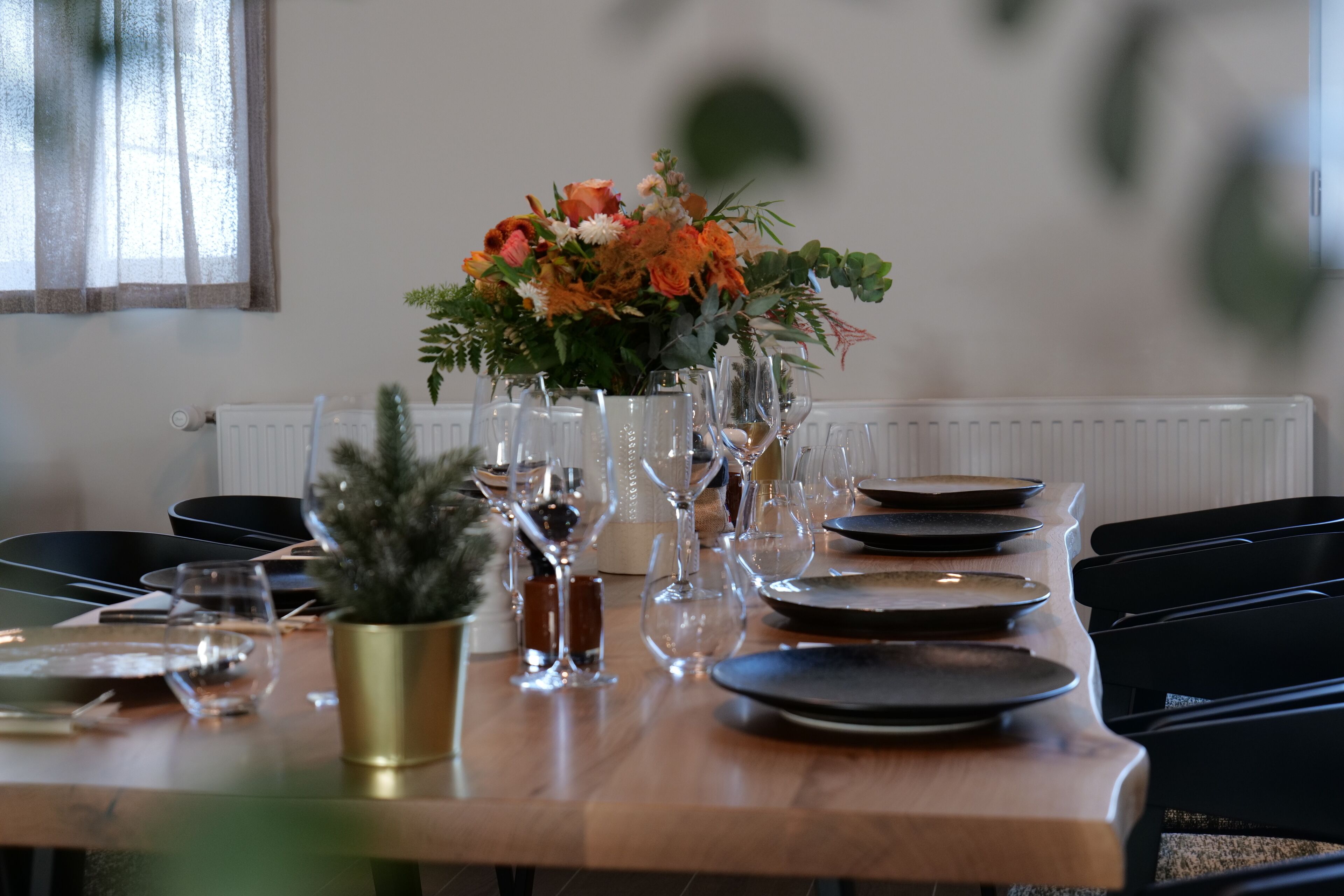 A dining table set with plates, glasses, and a centerpiece of flowers.