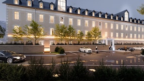 A large hotel with multiple floors, a parking lot, and a well-lit entrance. - Garrigae Caserne de Briançon & Spa - les Cinq Mondes (Briançon)