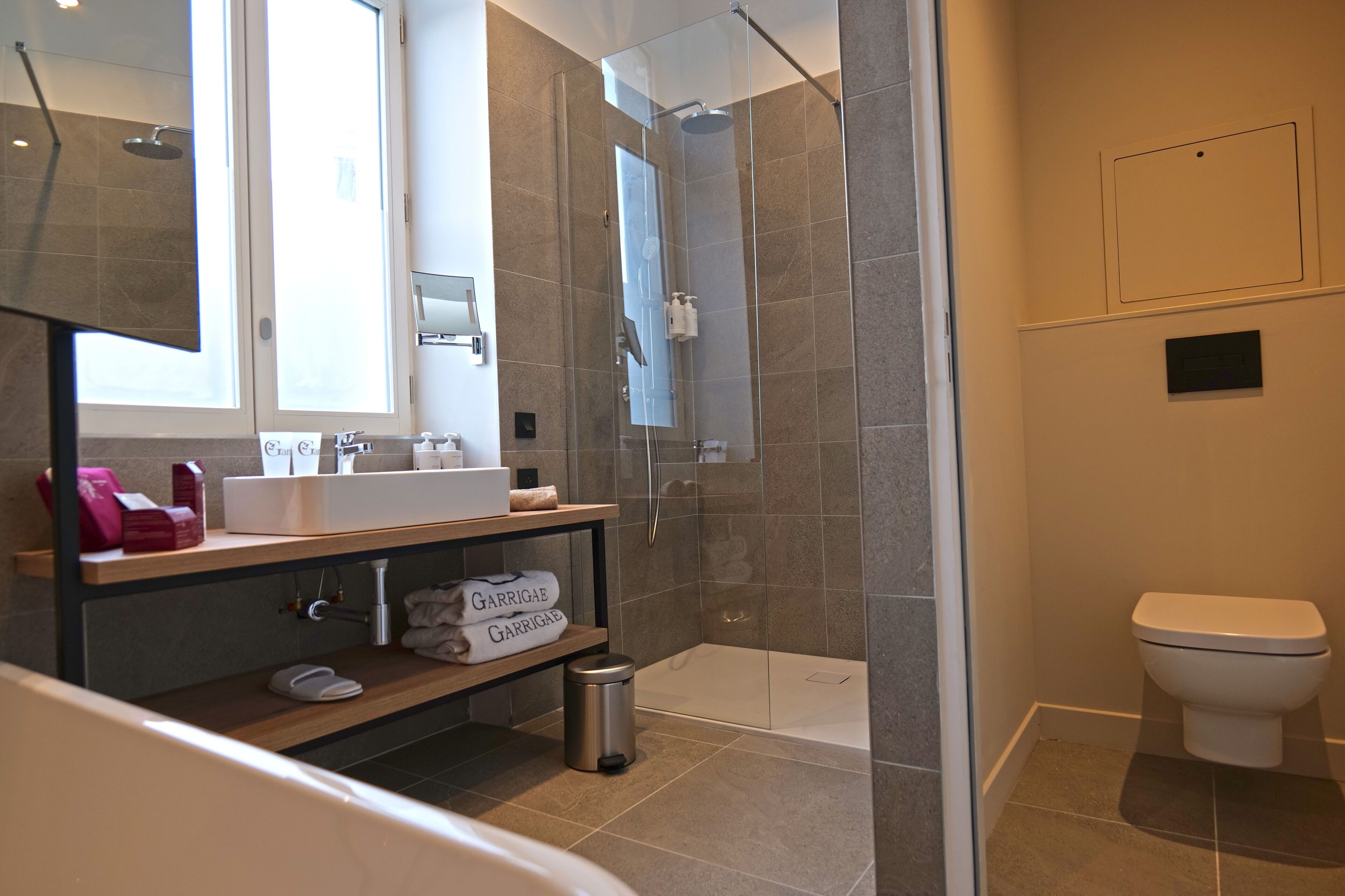 A modern bathroom with a glass-enclosed shower, a white sink, and a toilet.