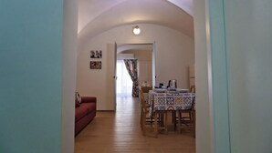 A room with a red sofa, a dining table with chairs, and a ceiling with a unique curved design.