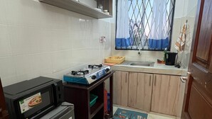 A compact kitchen with a refrigerator, microwave, gas stove, and wooden cabinets. - Fully furnished onebedroom in Mombasa Bamburi Vescone1 estate (Mombasa)