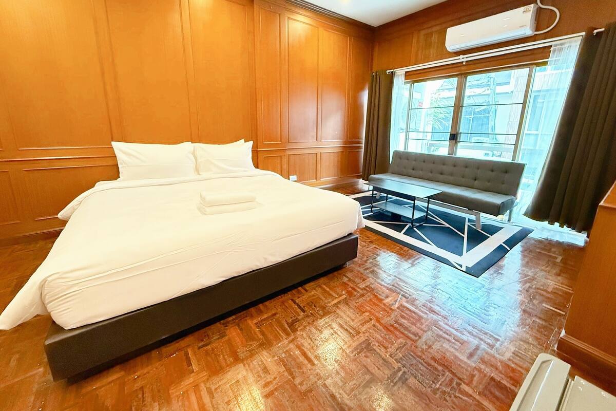 A hotel room with a large bed, a sofa, and a window with curtains.