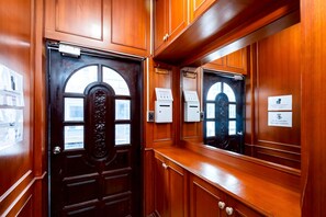 A wooden interior corridor with a door, a mirror, and a sign indicating a key return. - Stay On Sukhumvit 11 (Bangkok)
