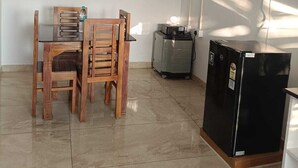 Une pièce comprenant une table à manger et des chaises, un ventilateur de plafond, un réfrigérateur et un distributeur d’eau.