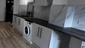 A modern kitchen with white cabinets, a marble backsplash, and a black countertop. - Modern Studio, Free Parking! (Rushden)