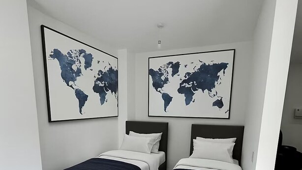 A modern bedroom with two beds, wooden flooring, and world map artwork on the walls. - Modern Studio, Free Parking! (Rushden)