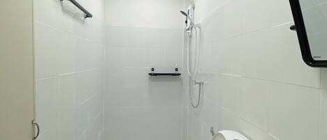 A small, white-walled bathroom with a toilet, sink, and shower.