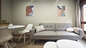 A living room with a grey sofa, white chairs, a small round table, and abstract art on the walls. - Desconectaengalicia Castiñeiros (Sanxenxo)