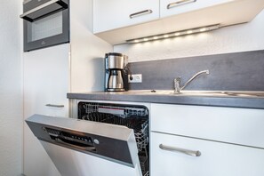 A modern kitchen with a dishwasher, a coffee maker, and a sink. - Apartment 'Hochparterre' with Sea View, Balcony and Wi-Fi (Cuxhaven)