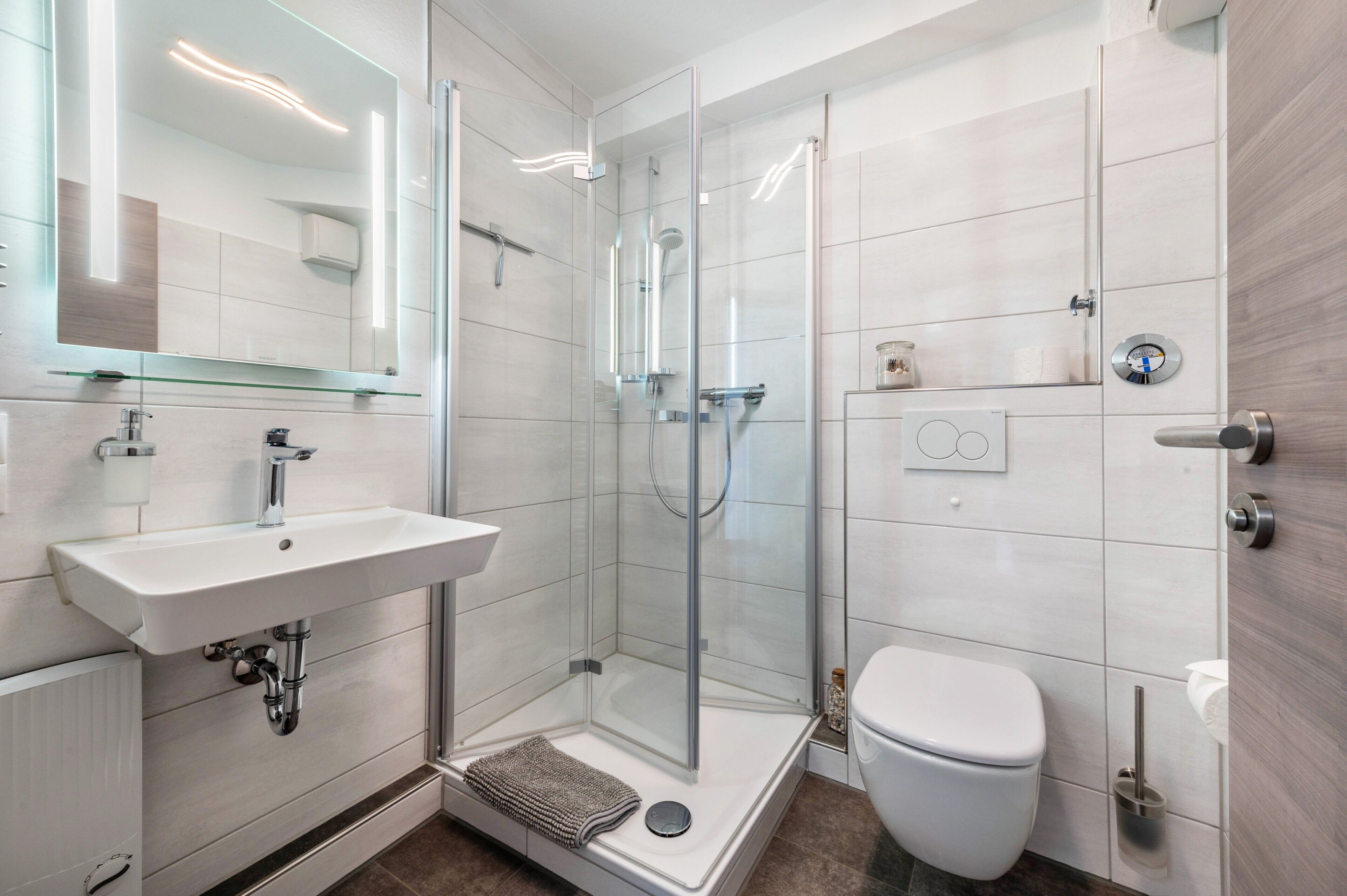 A modern bathroom with a glass-enclosed shower, a white sink, and a toilet.