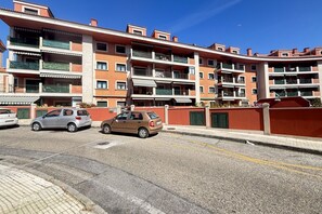 Ein mehrstöckiges Wohngebäude mit Balkonen, einem Parkplatz und blauem Himmel.