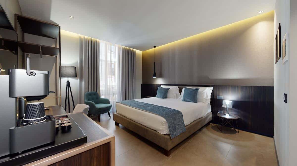 A modern hotel room with a large bed, bedside tables, a desk, and a chair.
