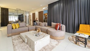 Un salon moderne avec un canapé d’angle, une table basse et un fauteuil jaune.