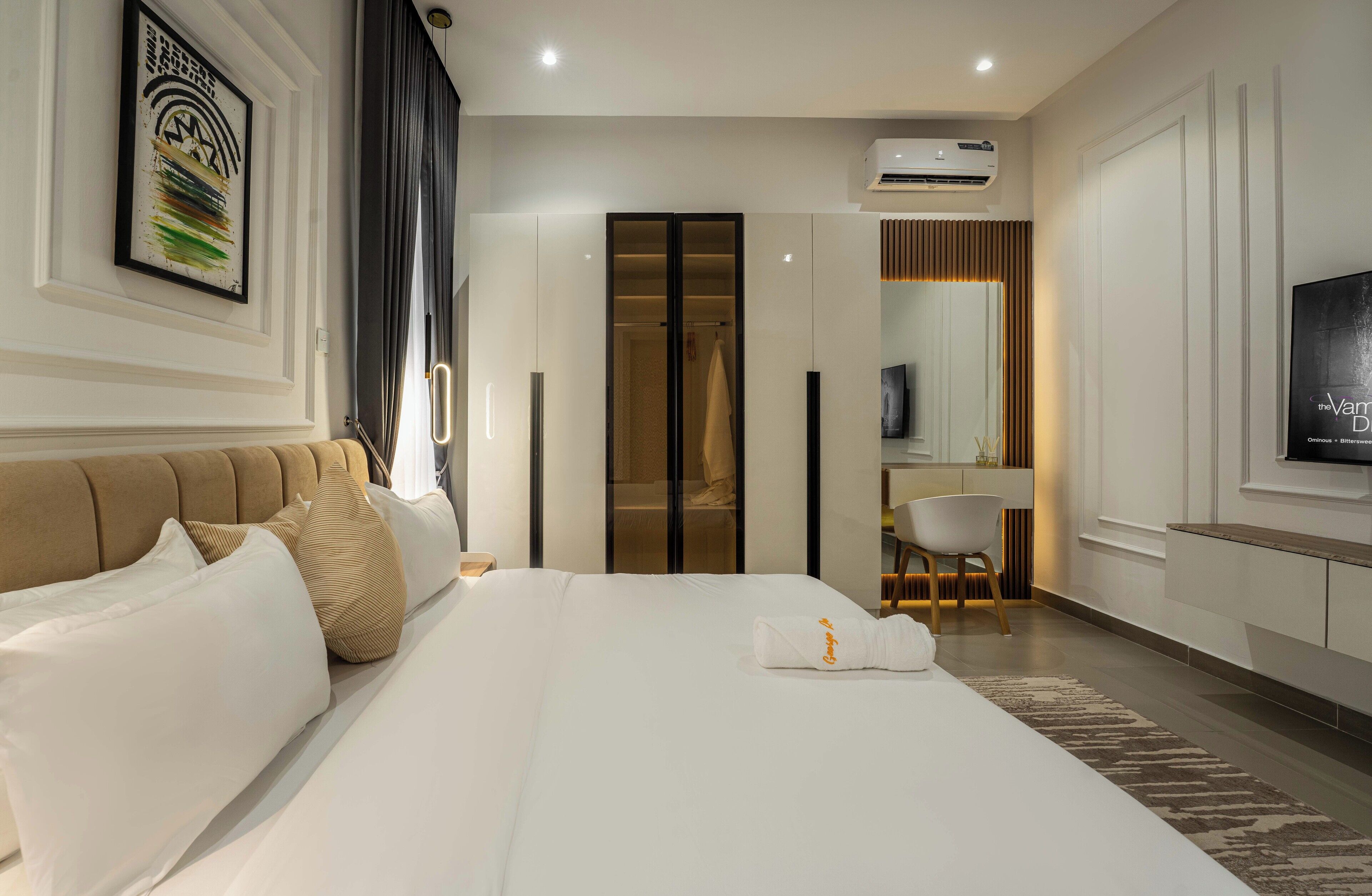 A hotel room with a large bed, a wardrobe, a desk, and a television.