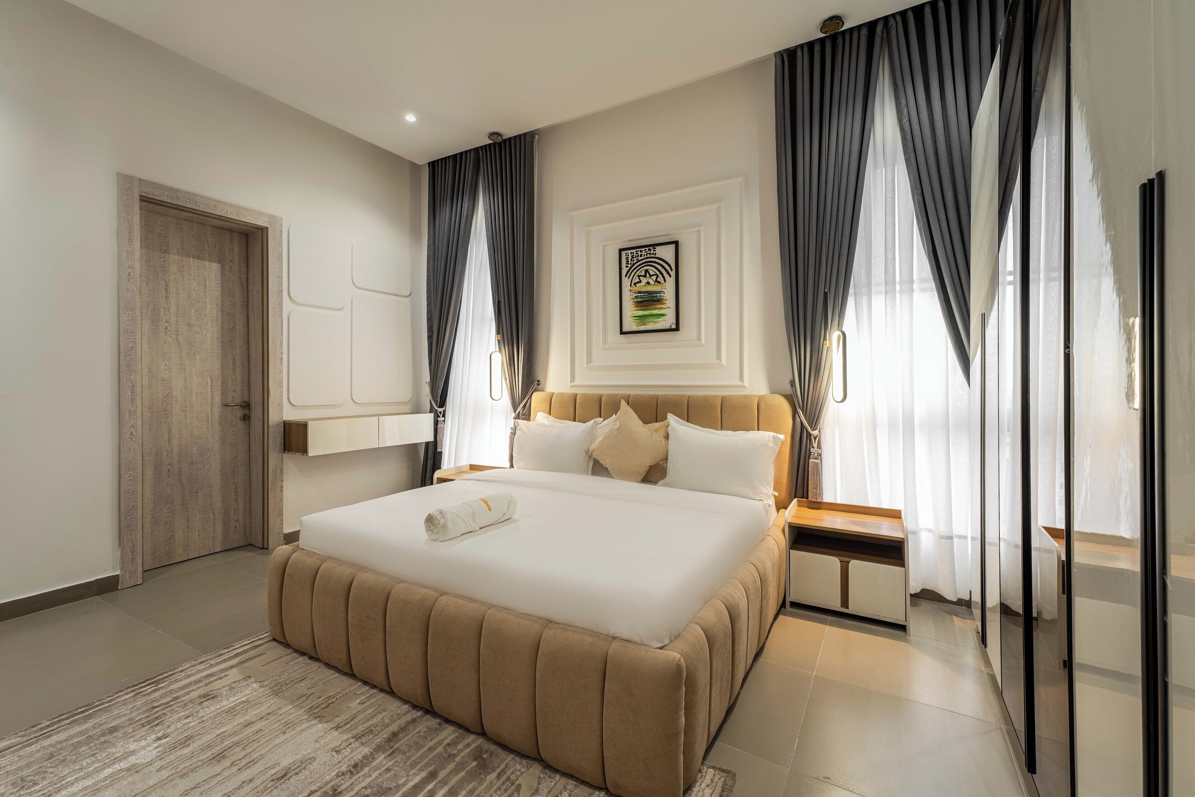 Une chambre d’hôtel moderne avec un grand lit, une table de chevet, un miroir et une porte.