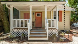 A small house with a porch, a front door, and a small garden area.