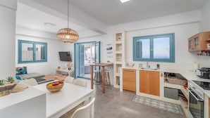 A modern kitchen with white cabinets, blue window frames, and a central island with stools. - Villa Etoni, stunning sea views, infinity pool and privacy (Kalamitsi)