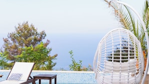 A poolside area with a lounge chair, a small table, and a white hanging chair. - Villa Etoni, stunning sea views, infinity pool and privacy (Kalamitsi)