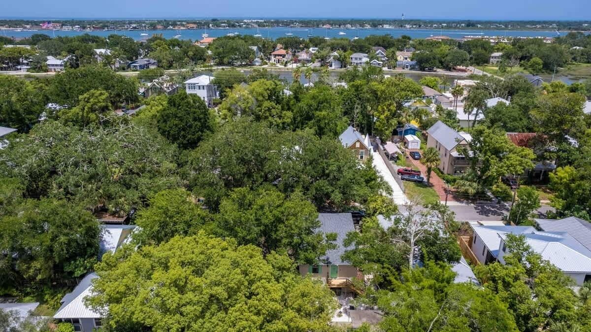 A residential area with houses surrounded by trees and a view of the sea.
