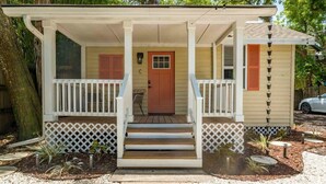 A small house with a porch, a front door, and a small garden area.