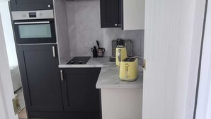 A compact kitchen with dark cabinets, a built-in oven, a sink, and a yellow toaster. - Yellow Studio - Wembley Stadium - London (Wembley)