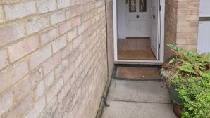 A narrow brick corridor leading to a white door with a small step and a doormat. - Yellow Studio - Wembley Stadium - London (Wembley)