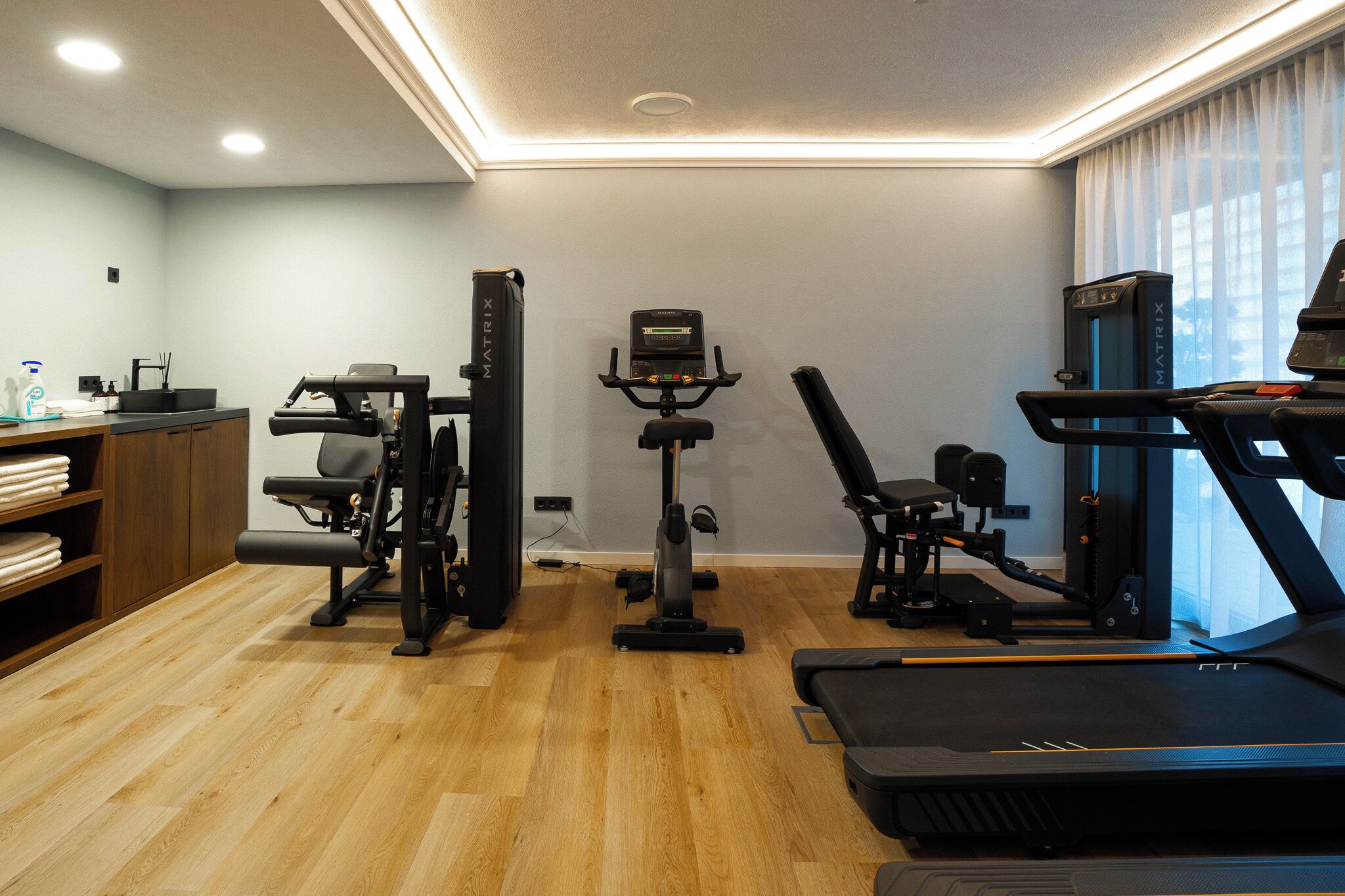 A home gym with a treadmill, stationary bike, and weight machine.