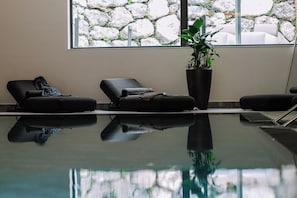 A pool area with lounge chairs and a potted plant.