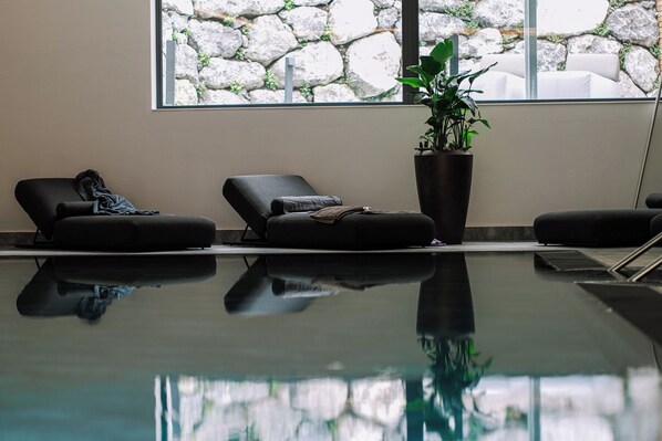 A pool area with lounge chairs and a potted plant.