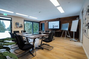 A conference room with a large table, chairs, a projector screen, and a whiteboard.