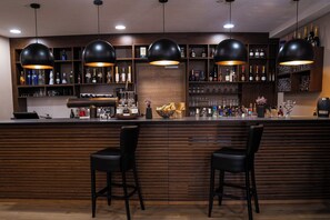 A bar area with wooden paneling, black bar stools, and pendant lighting. - Allgäuer Bergwald Chalets  (Oberstaufen)