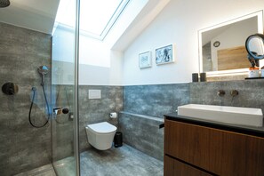 Un baño moderno con cabina de ducha de vidrio, inodoro y tocador con espejo.