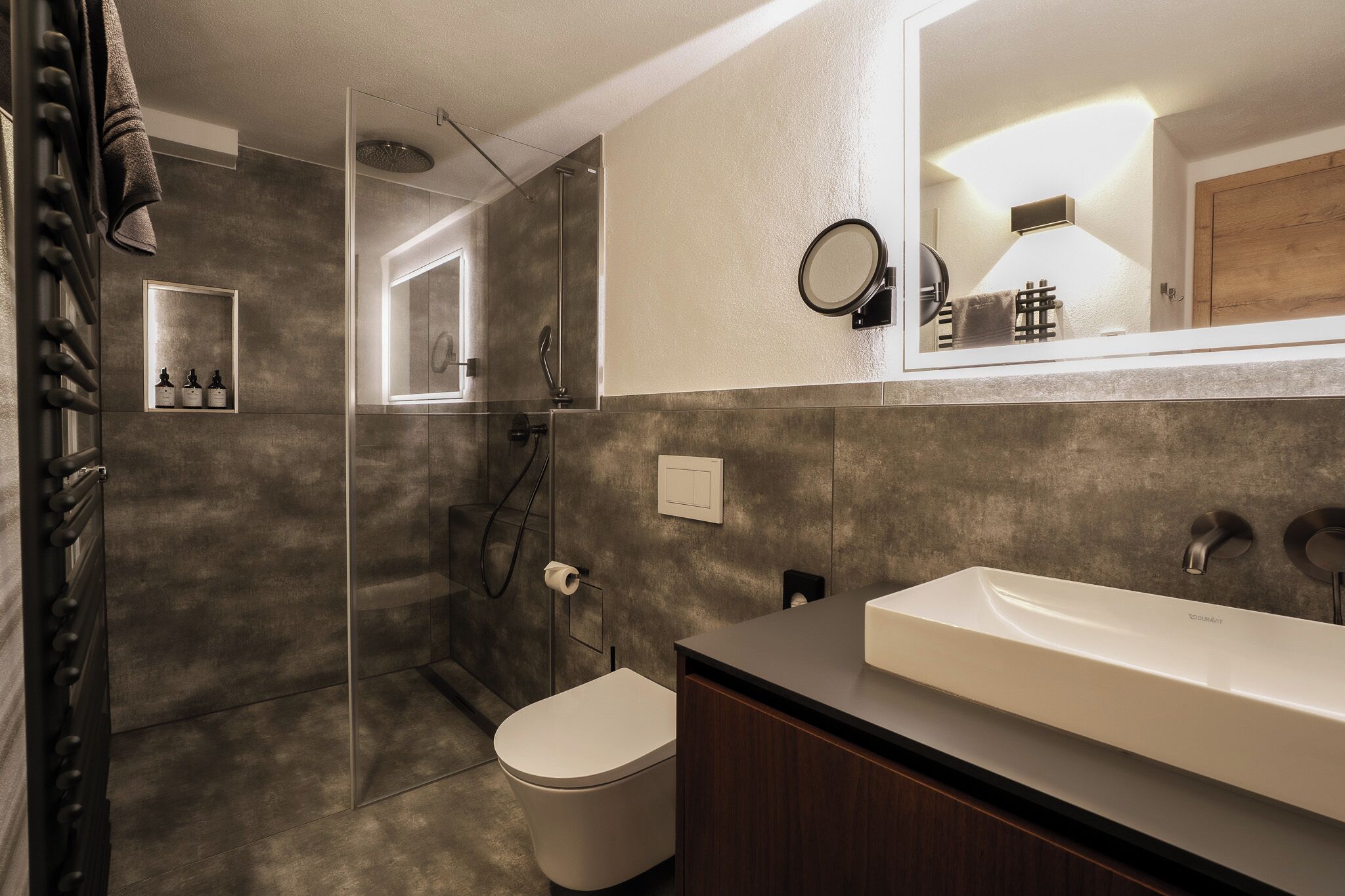 A modern bathroom with a walk-in shower, a toilet, a sink, and a mirror.