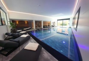 Un área de piscina interior moderna con asientos y vistas al exterior.