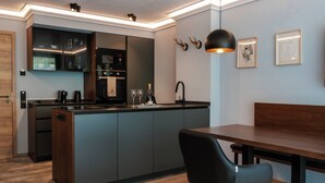 A modern kitchen with a built-in island, a dining area with a bench, and a pendant light. - Allgäuer Bergwald Chalets  (Oberstaufen)