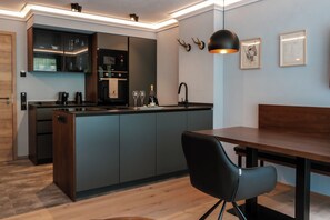 A modern kitchen with a built-in island, a dining area with a bench, and a pendant light. - Allgäuer Bergwald Chalets  (Oberstaufen)