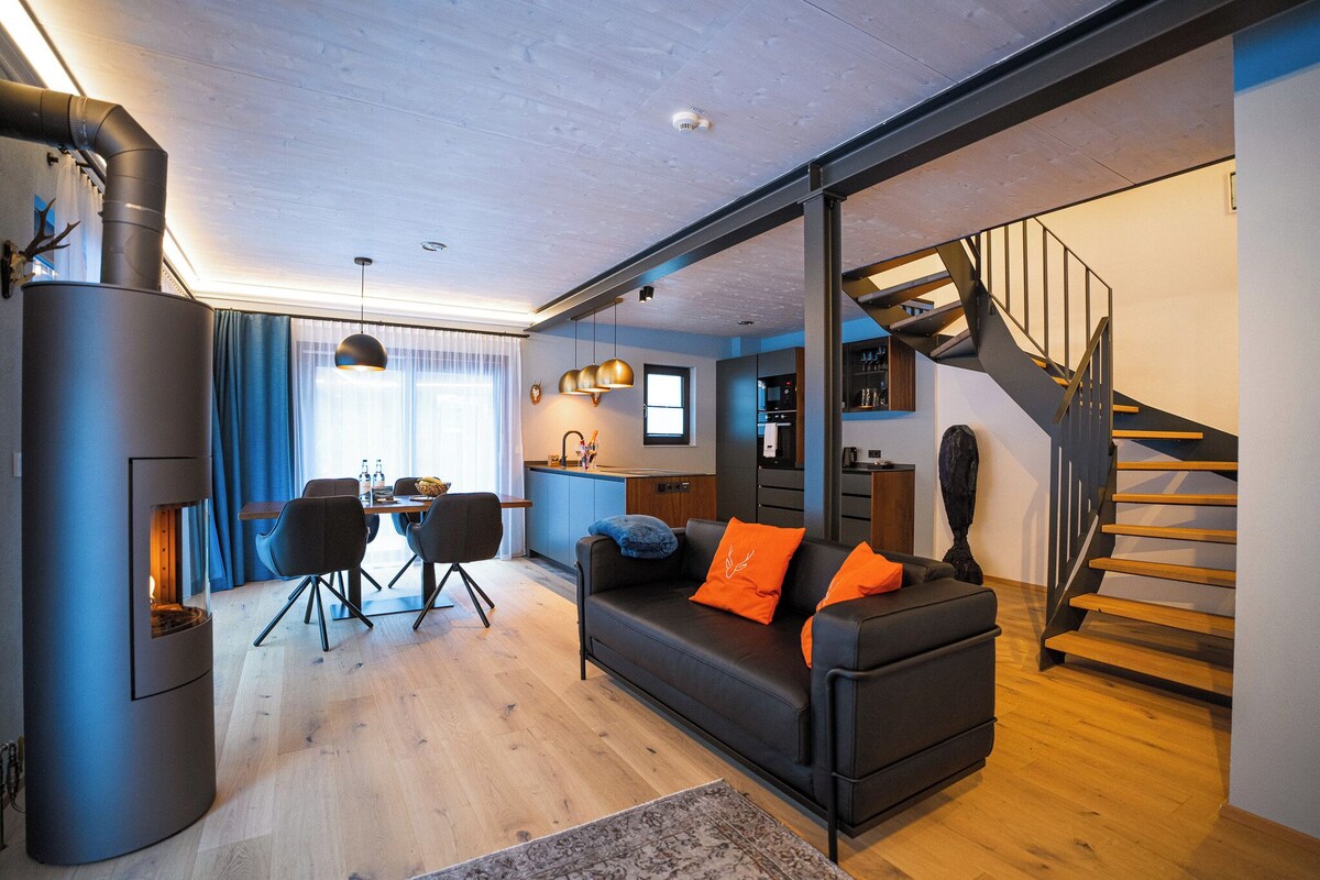 Una sala de estar moderna con un sofá, una mesa de comedor y una escalera.