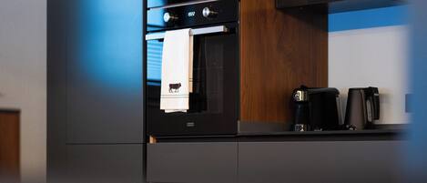 A modern kitchen with a built-in oven, a coffee machine, and a microwave.