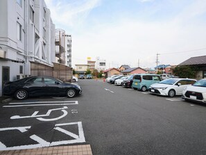 A parking lot with cars and a building with multiple floors. - Okasan Hotel (Ogaki)