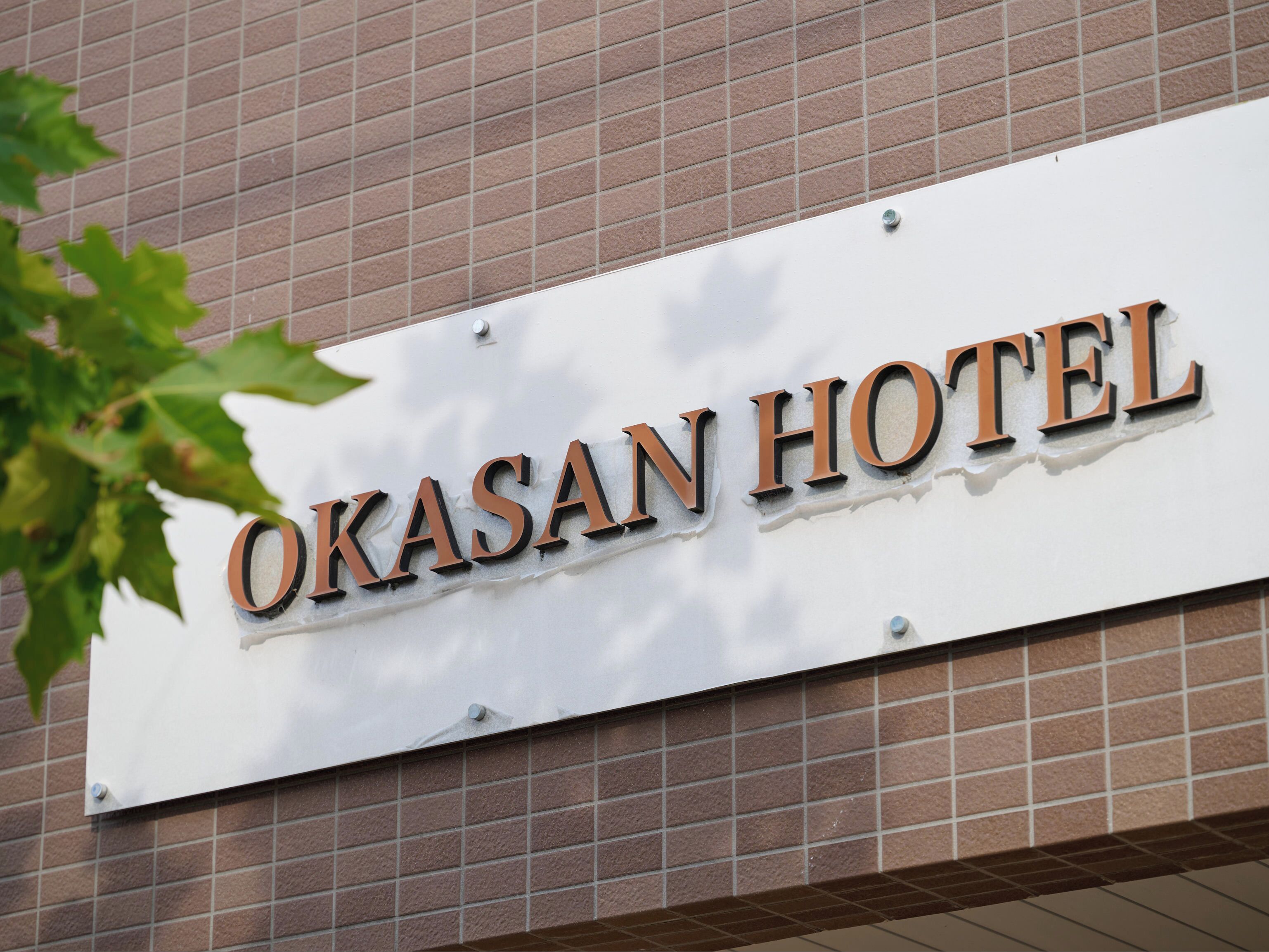 Segnaletica dell'Hotel Okasan, con la scritta del nome ben visibile in caratteri grandi e in grassetto.