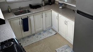 A kitchen with white cabinets, a stainless steel sink, a stove, and a refrigerator. - Dolly’s Place perfect to unwind (Bayville)
