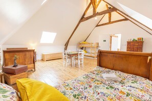 A cozy attic bedroom with a sloped ceiling, a bunk bed, a desk, and a dresser.
