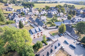 An aerial view of a village with traditional architecture, a central square, and parked cars.