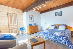 A cozy room with a bed, a wooden dresser, a chair, and a table.