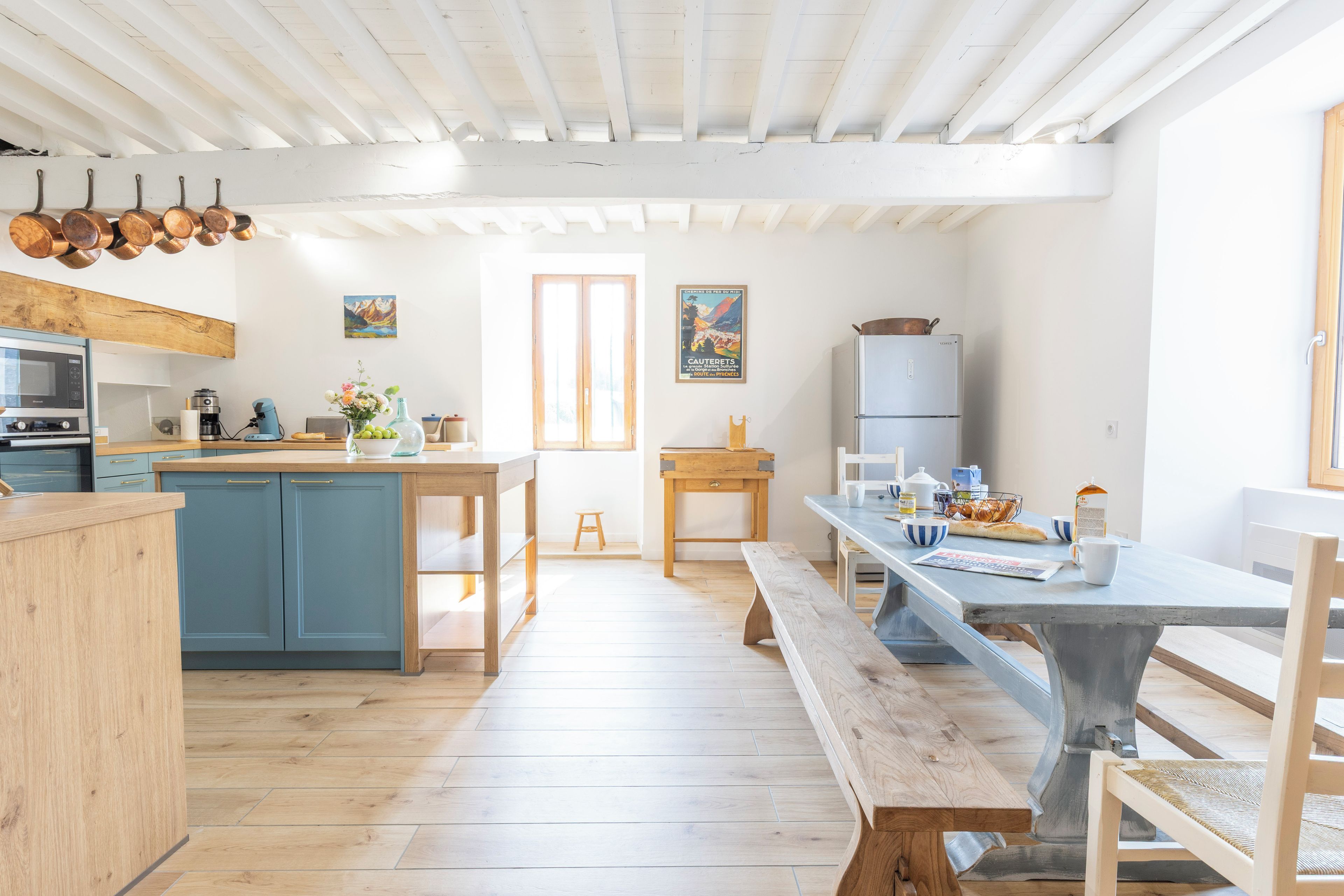 A kitchen with wooden cabinets, a dining table, and a bench.
