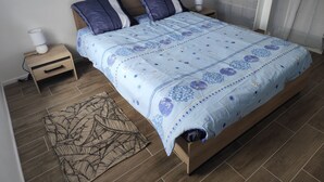 A bedroom with a bed, two nightstands, a lamp, and a patterned rug. - Gîte Le Magnolia (Ploërmel)