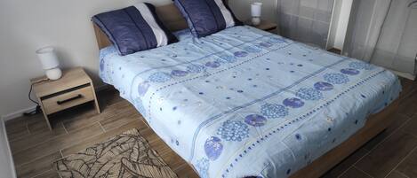 Une chambre à coucher avec un lit, deux tables de chevet, une lampe et un tapis à motifs.